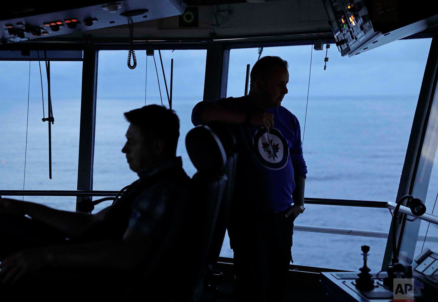  In this Thursday, July 6, 2017 photo, first officer Jukka Vuosalmi, right, and second officer Ilkka Alhoke look out from the bridge during a night shift while piloting the Finnish icebreaker MSV Nordica as it sails the North Pacific Ocean to travers