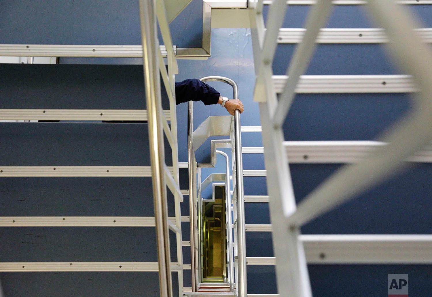In this Wednesday, July 12, 2017 photo, Nigel Greenwood, assistant ice navigator and retired Royal Canadian Navy rear admiral, climbs down the six flights of stairs from the bridge to the mess hall as he heads down for dinner aboard the Finnish icebreaker MSV Nordica as it sails the Bering Sea to traverse the Northwest Passage through the Canadian Arctic Archipelago. (AP Photo/David Goldman)