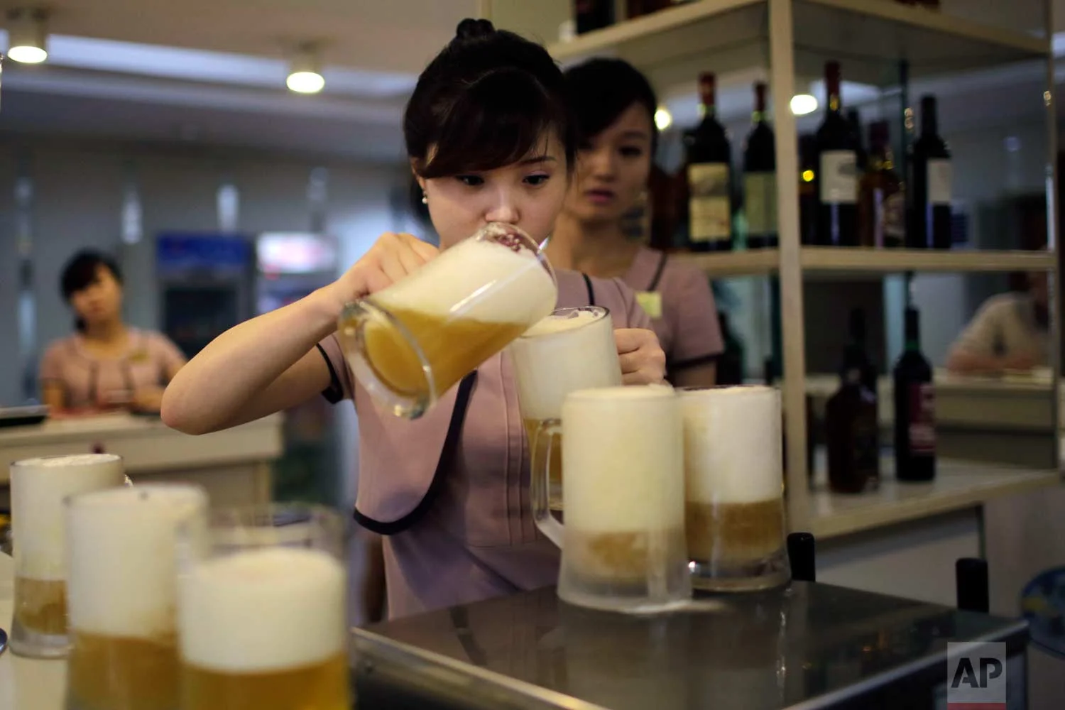 In this Wednesday, July 26, 2017, photo, a waitress pours a new type of Taedonggang beer, the eighth in its line of specialty brews, made of wheat and hops at the Taedonggang Brewery in Pyongyang, North Korea. (AP Photo/Wong Maye-E)