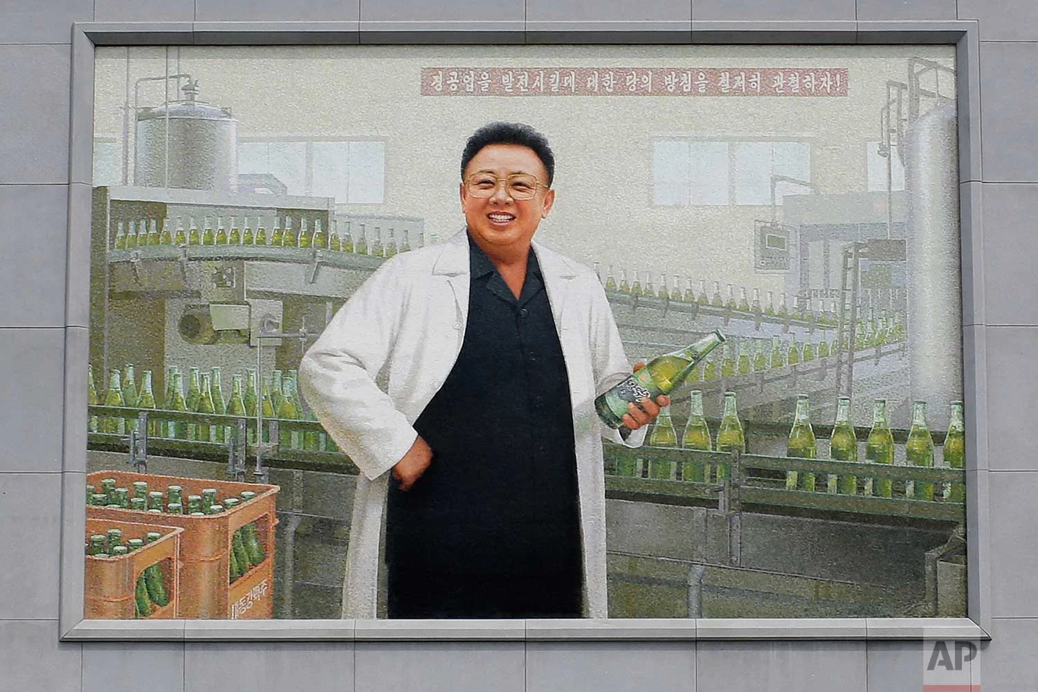 In this Wednesday, July 26, 2017, photo, a mural of the late North Korean leader Kim Jong Il in a white lab coat holding up a bottle of beer is seen at the entrance of the Taedonggang Brewery in Pyongyang, North Korea. (AP Photo/Wong Maye-E)