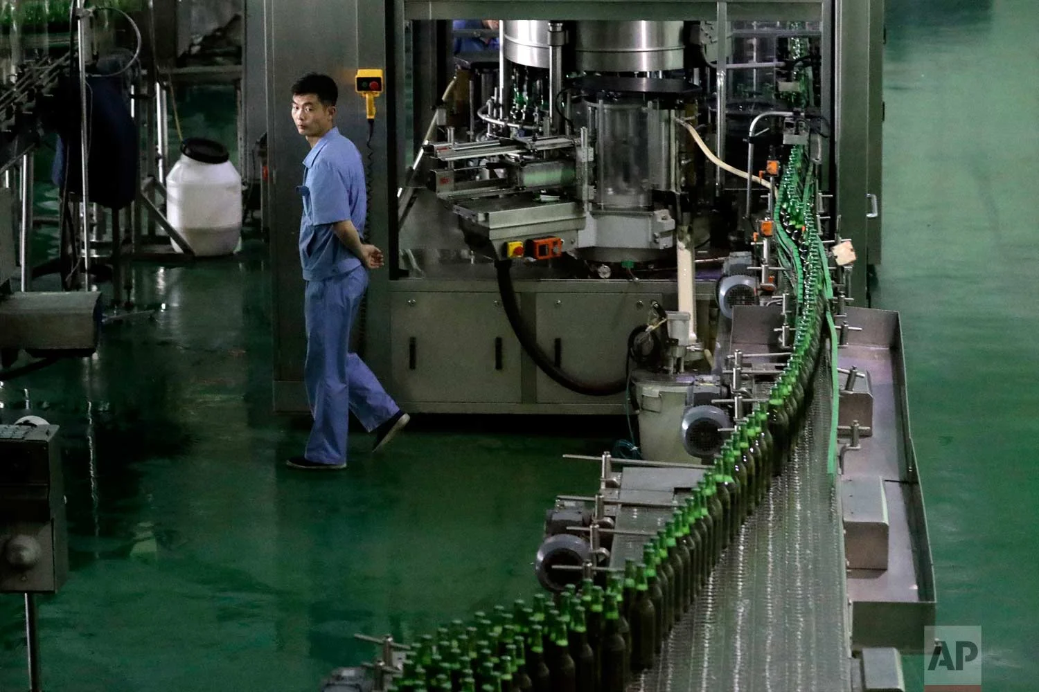 In this Wednesday, July 26, 2017, photo, a worker monitors a conveyor belt where bottles of beer are transported at the Taedonggang Brewery in Pyongyang, North Korea. (AP Photo/Wong Maye-E)