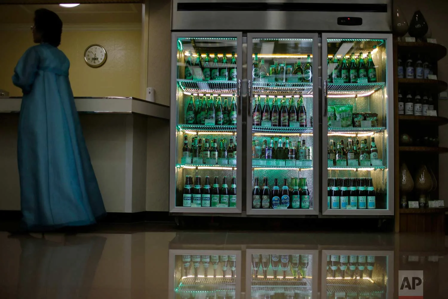 In this Wednesday, July 26, 2017, photo, a factory guide stands next to a refrigerator containing different types of beer produced at the Taedonggang Brewery in Pyongyang, North Korea. (AP Photo/Wong Maye-E)