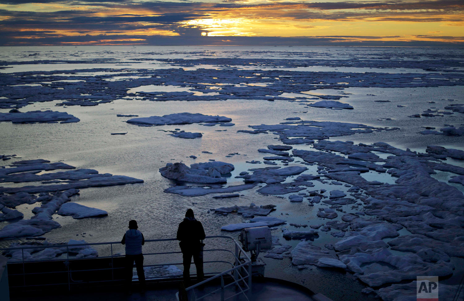 Researchers look out from the Finnish icebreaker MSV Nordica as the sun sets over sea ice floating on the Victoria Strait along the Northwest Passage in the Canadian Arctic Archipelago, Friday, July 21, 2017. Sea ice plays an important role in the global climate system by cooling the surrounding water and air. It helps maintain ocean and atmospheric currents that affect weather which is characteristic for certain parts of the world, such as the comparatively mild temperatures found in western Europe. (AP Photo/David Goldman) 