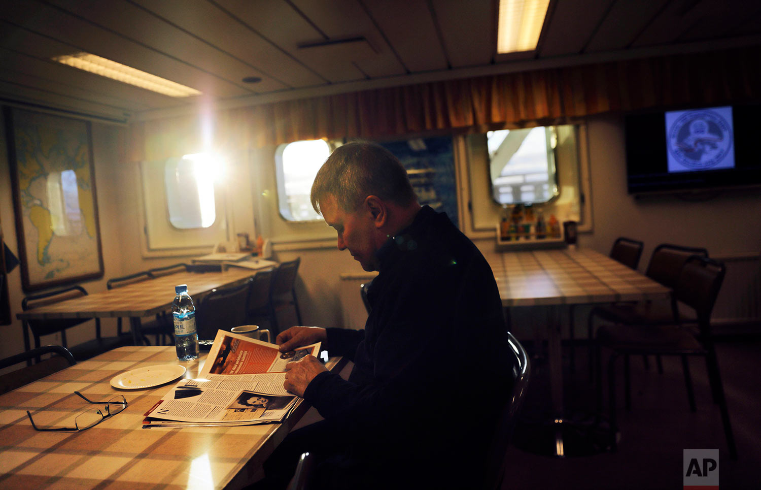  The sun shines through the window of the mess hall at midnight as first engineer Kari Suni reads a magazine over a cup of coffee before starting his shift in the engine room of the Finnish icebreaker MSV Nordica as it traverses the Northwest Passage