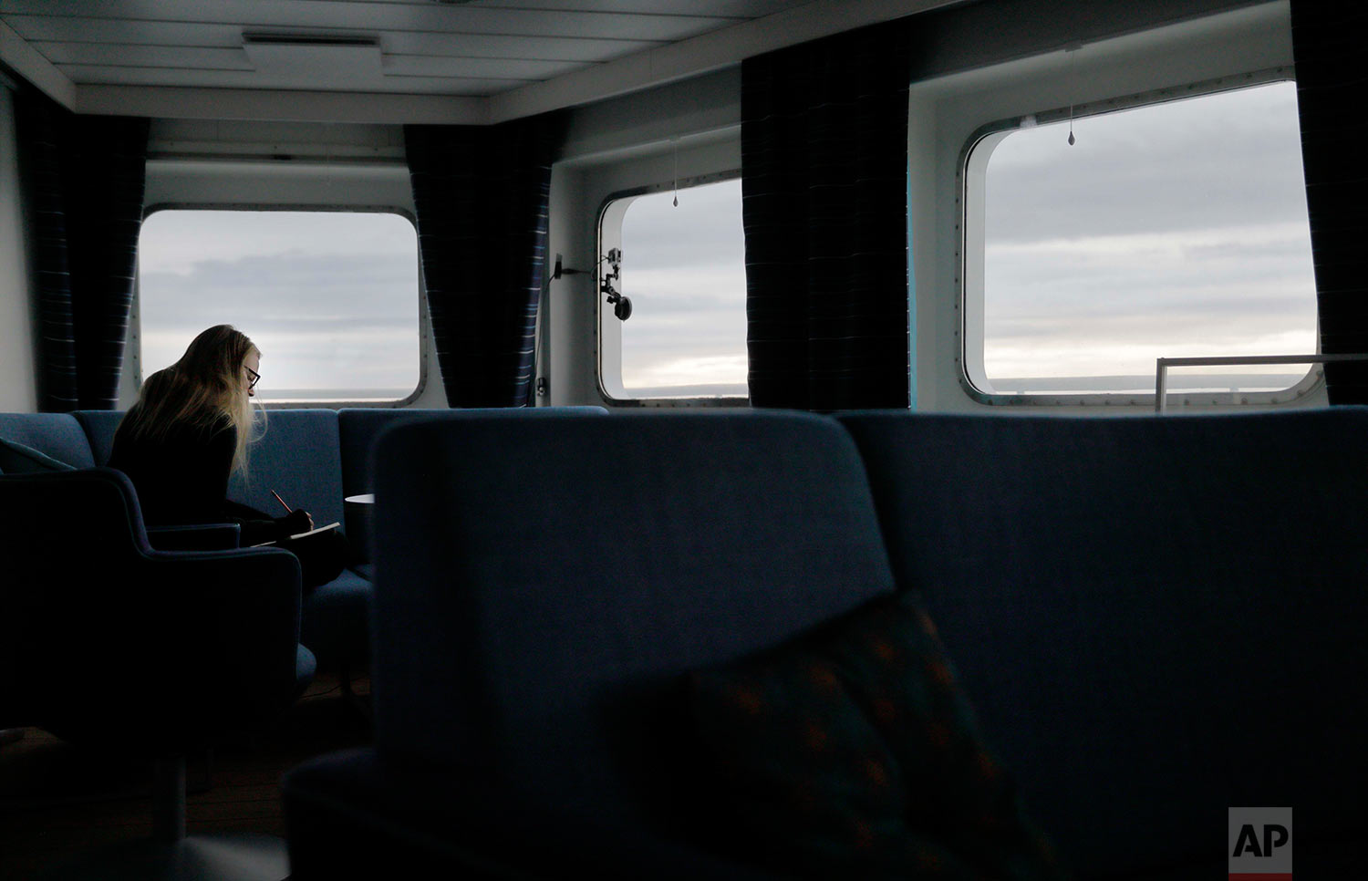  Daylight lingers behind the clouds at midnight as researcher Tiina Jaaskelainen writes in her diary aboard the Finnish icebreaker MSV Nordica while traversing the Northwest Passage though the Canadian Arctic Archipelago, early Monday, July 24, 2017.