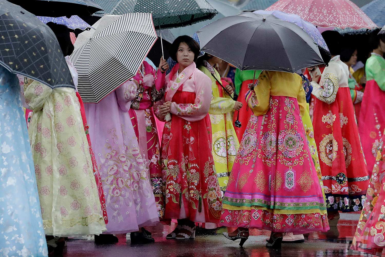 University students wearing traditional Korean dresses wait in the rain for the start of a group dance on Thursday, July 27, 2017, in Pyongyang, North Korea as part of celebrations for the 64th anniversary of the armistice that ended the Korean War. (AP Photo/Wong Maye-E)