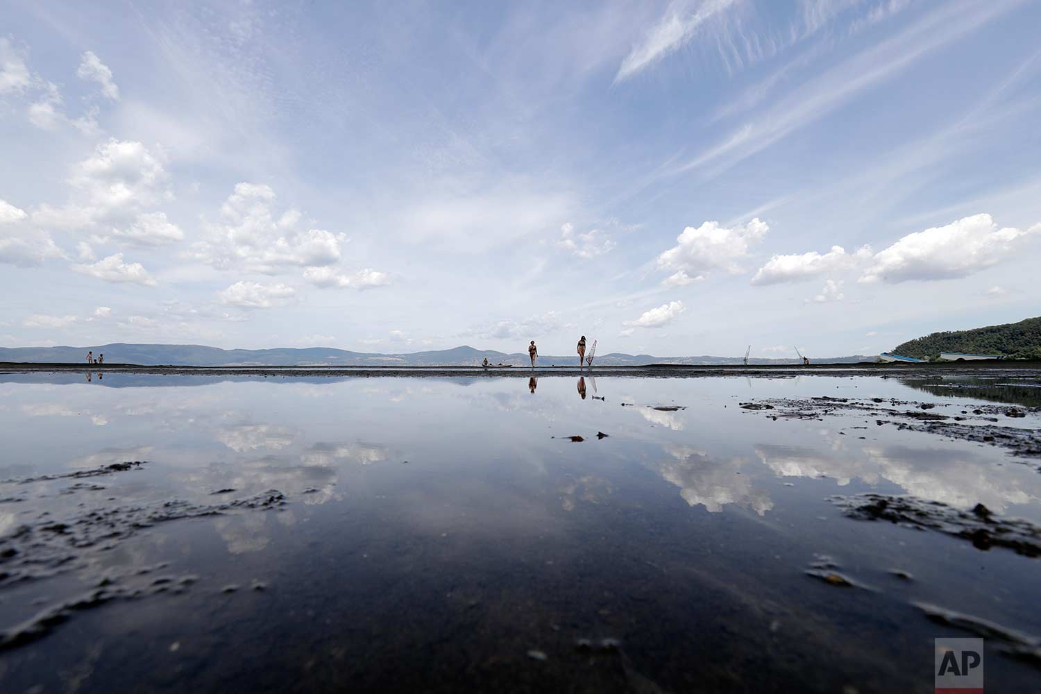 People walk along the shore of Lake Bracciano, about 35 kilometers (22 miles) northwest of Rome, Thursday, July 27, 2017. (AP Photo/Andrew Medichini)