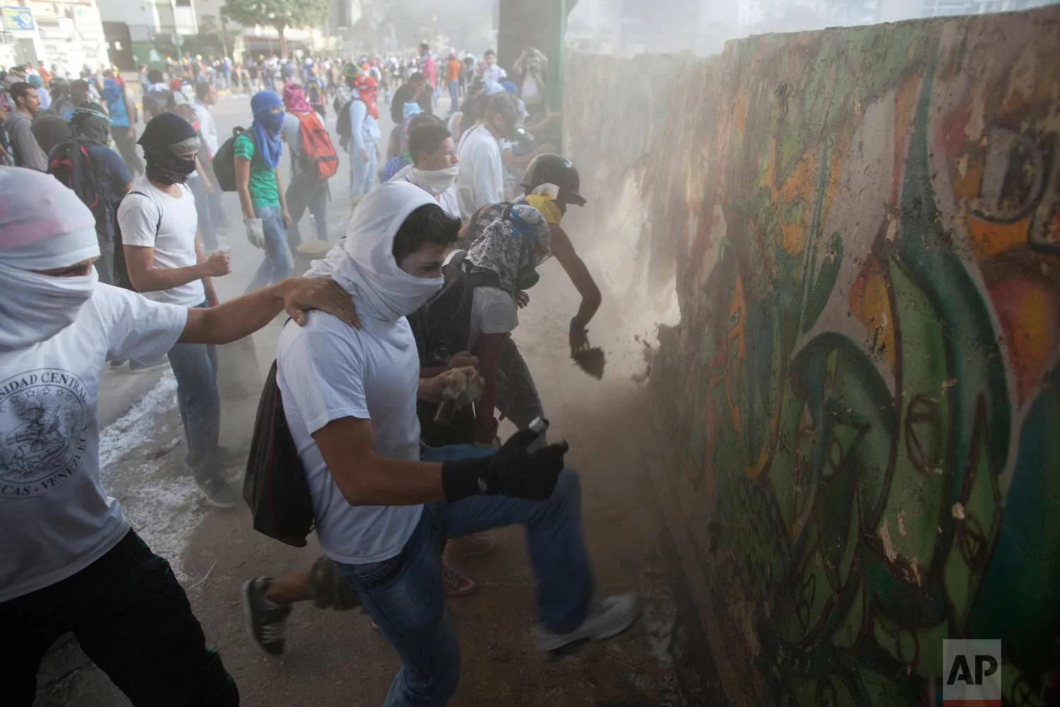 In this March 4, 2014 photo, demonstrators destroy a wall in order to have more rocks to throw at the Bolivarian National Guard during anti-government protests in Caracas, Venezuela, one year after the death of Hugo Chavez. (AP Photo/Rodrigo Abd)