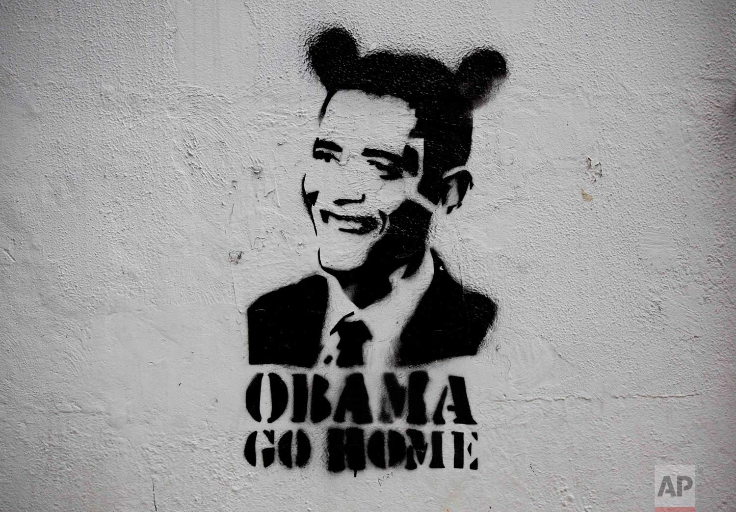 An image of President Barack Obama wearing fake ears and the slogan “Obama go home” on a street wall in Caracas, Venezuela. (AP Photo/Ariana Cubillos)