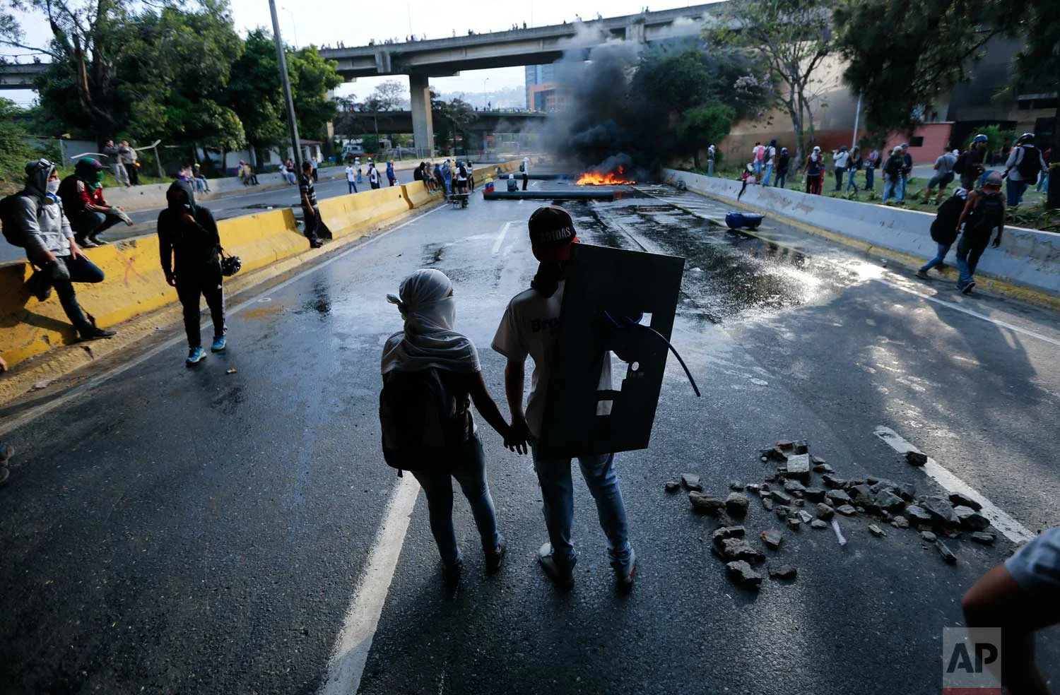 A couple holds hands at a road block set by anti-government protesters in Caracas, Venezuela. Protesters shut down the capital city’s main highway to express their disgust with the administration of President Nicolas Maduro. (AP Photo/Ariana Cubillos)