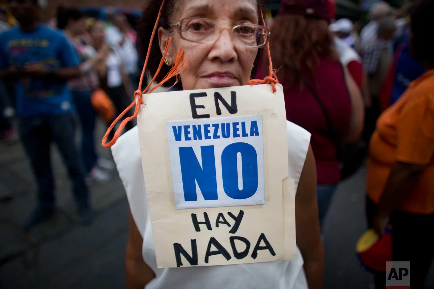 In this Aug. 8, 2015 photo, Beatriz Silva, 74, wears a sign that reads in Spanish: "In Venezuela, there's nothing" as she joins a protest in Caracas, Venezuela. Anti-government protesters are denouncing food shortages and violence. (AP Photo/Ariana Cubillos)