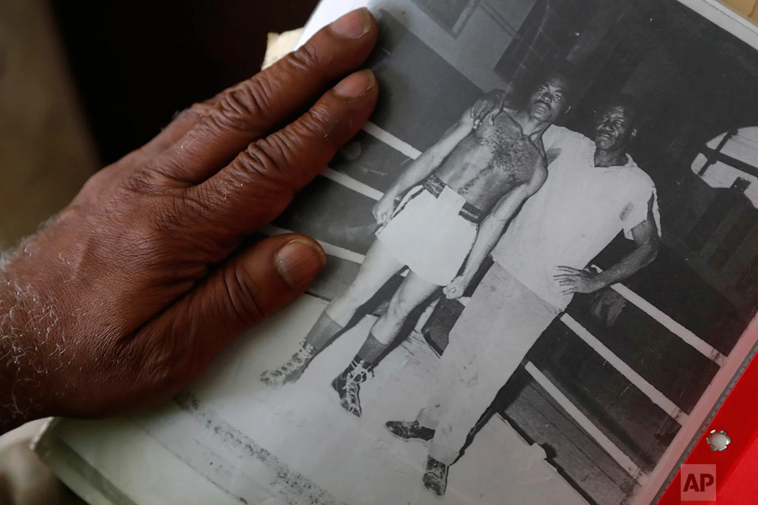  John Hall looks at a photo of himself, left, from boxing in prison at his house in Detroit, Friday, May 19, 2017. (AP Photo/Paul Sancya)
