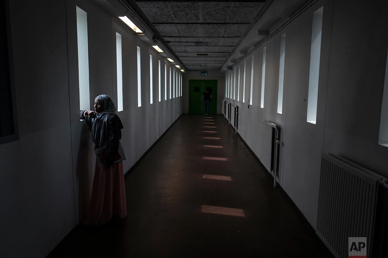 In this Thursday, July 13, 2017 photo, Ethiopian migrant Mako Husa, 40, looks out from a window of a corridor at the former prison of Bijlmerbajes in Amsterdam, Netherlands. (AP Photo/Muhammed Muheisen)
