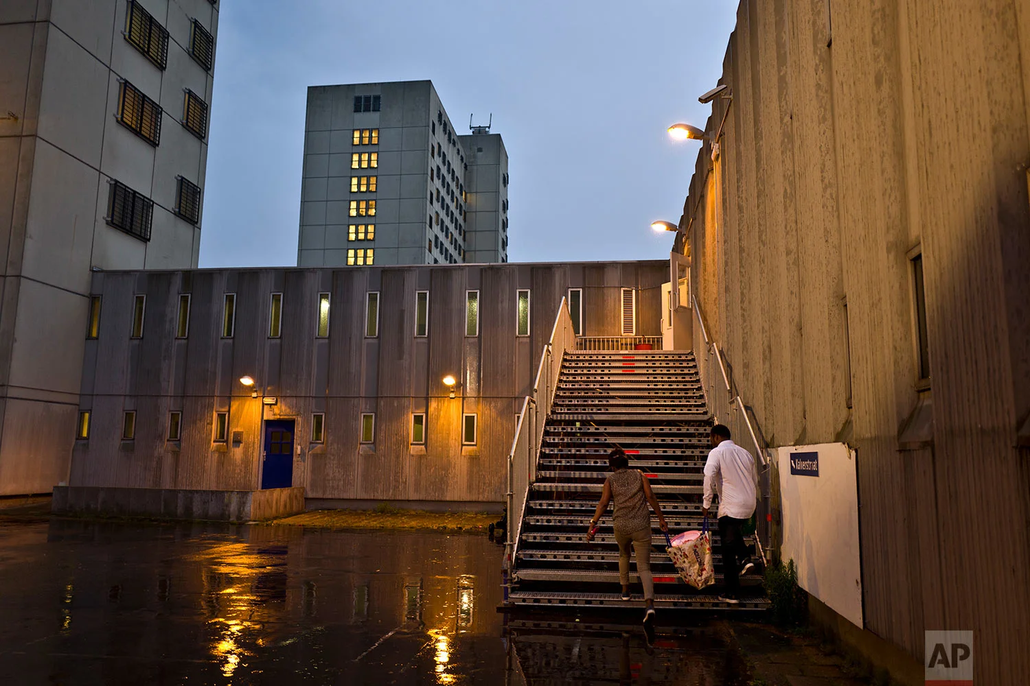 In this Thursday, July 6, 2017 photo, migrants carry a bag while walking back to their room at the former prison of Bijlmerbajes in Amsterdam, Netherlands. (AP Photo/Muhammed Muheisen)