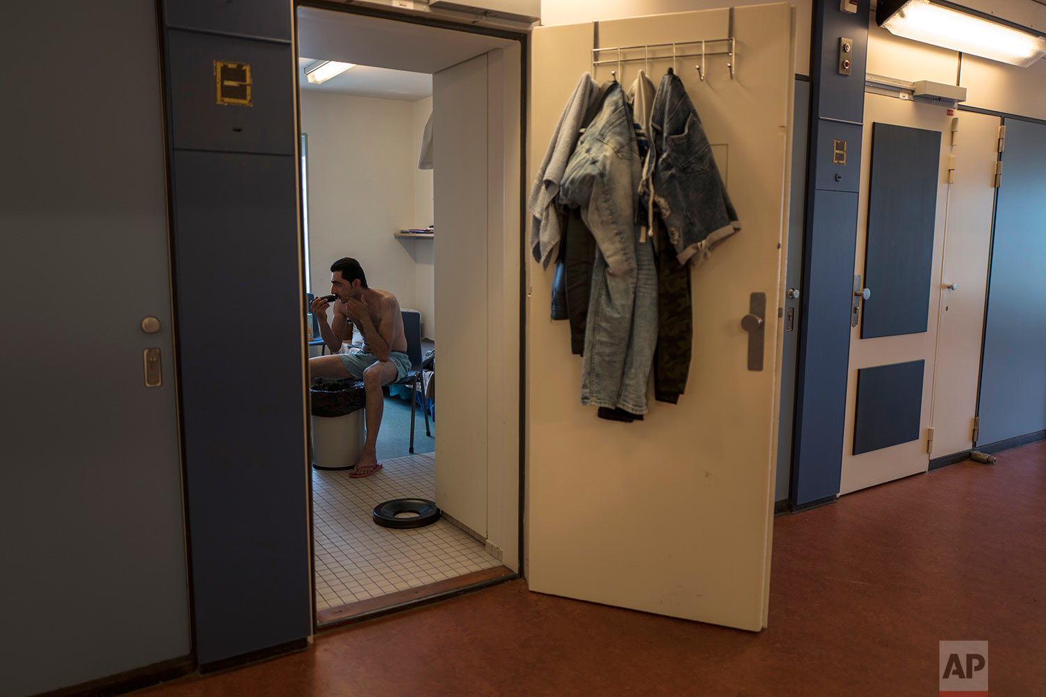In this Sunday, July 9, 2017 photo, Iranian migrant Adel Nazari, 32, trims his beard in his room at the former prison of Bijlmerbajes in Amsterdam, Netherlands. (AP Photo/Muhammed Muheisen)