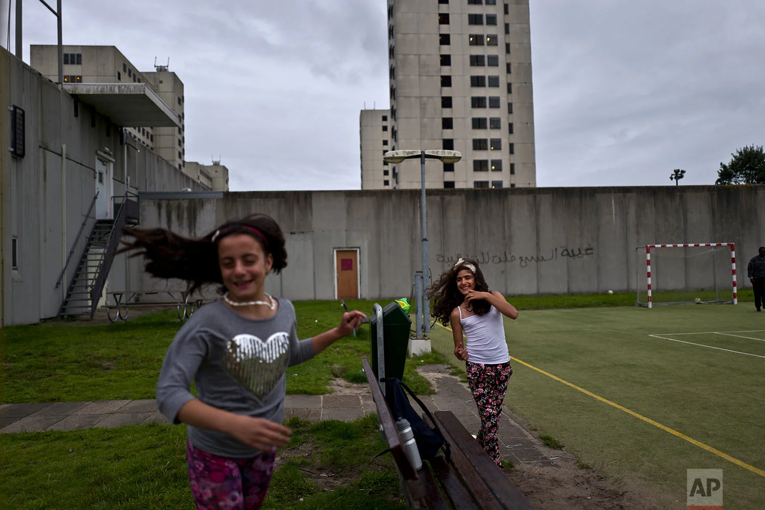 In this Friday, July 28, 2017 photo, Syrian refugee girls, Mishleen Samir, 10, right, from Damascus, and her friend Claire Alzain, 10, from Damascus, run after each other while playing in a yard at the former prison of Bijlmerbajes in Amsterdam, Netherlands. (AP Photo/Muhammed Muheisen)