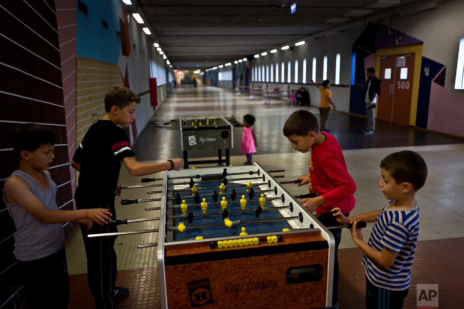 In this Monday, June 26, 2017 photo, refugee brothers from Baniyas, Syria, from right, Izzeldein Moustafa, 6, Abdulrahman, 10, Ahmad, 12 and Amir, 8, play table foosball in a corridor known as Kalverstraat, referring to a busy shopping street in Amsterdam, at the former prison of Bijlmerbajes in Amsterdam, Netherlands. (AP Photo/Muhammed Muheisen)