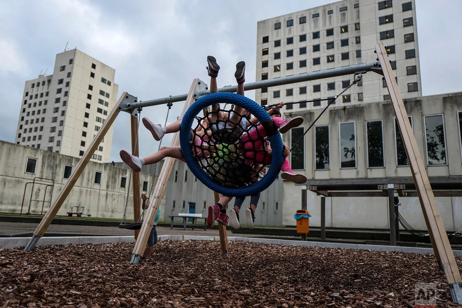 In this Thursday, July 20, 2017 photo, a group of Syrian refugee girls enjoy a swing ride in a yard at the former prison of Bijlmerbajes in Amsterdam, Netherlands. (AP Photo/Muhammed Muheisen)