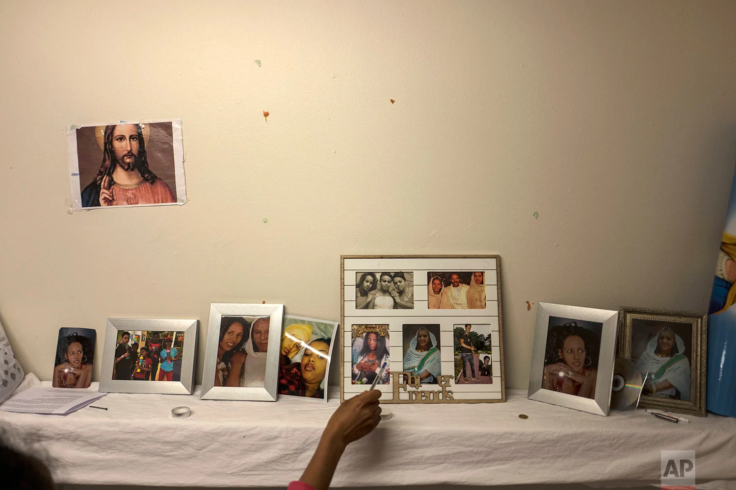 In this Sunday, July 9, 2017 photo, Eritrean migrant Ksanet Goitom, 23, points at pictures that she brought with her from Eritrea showing family members and friends, displayed at her room in the former prison of Bijlmerbajes in Amsterdam, Netherlands. (AP Photo/Muhammed Muheisen)