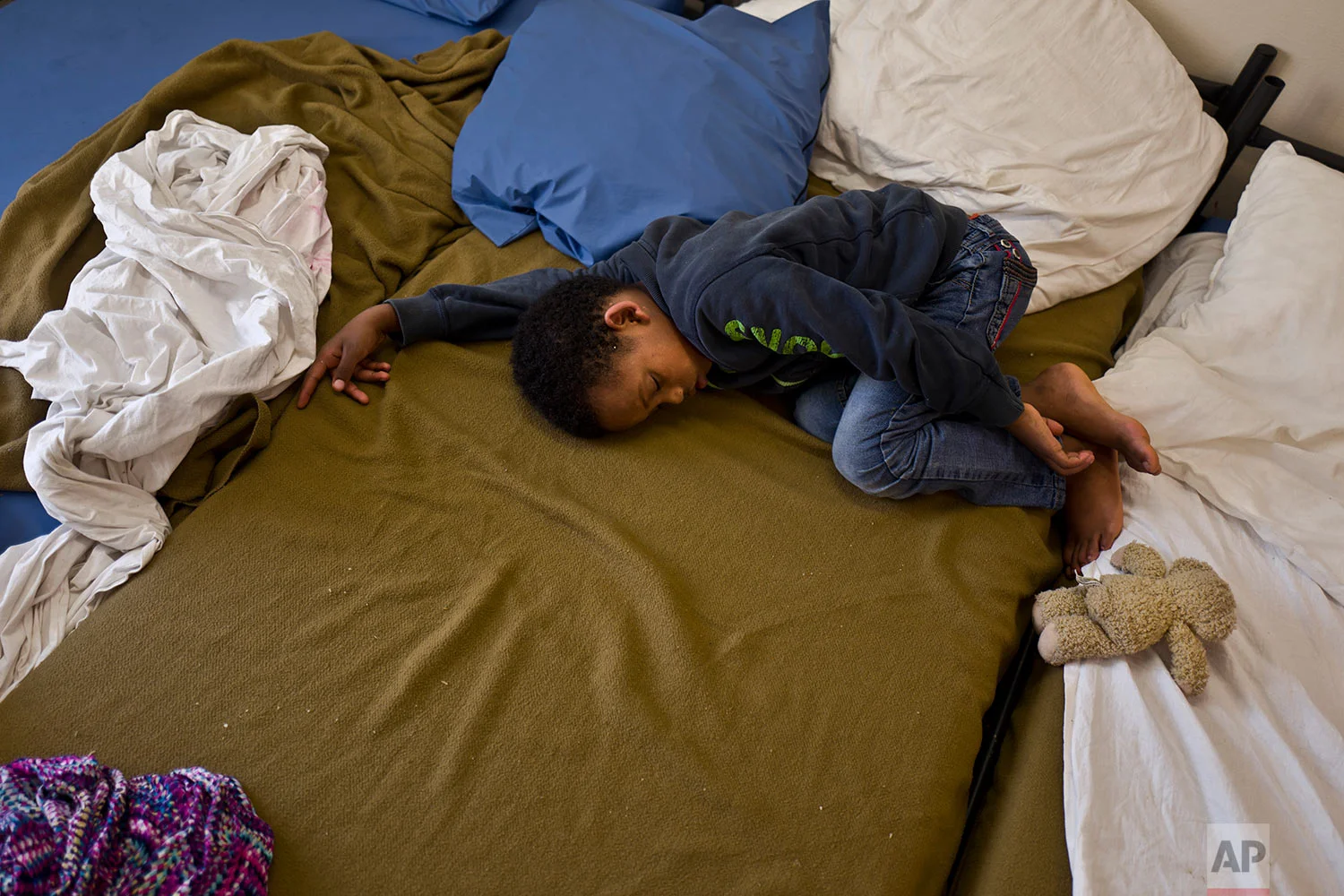 In this Friday, July 7, 2017 photo, Eritrean migrant Solomun Drat, 7, sleeps on a bed at his family's room in the former prison of Bijlmerbajes in Amsterdam, Netherlands. (AP Photo/Muhammed Muheisen)
