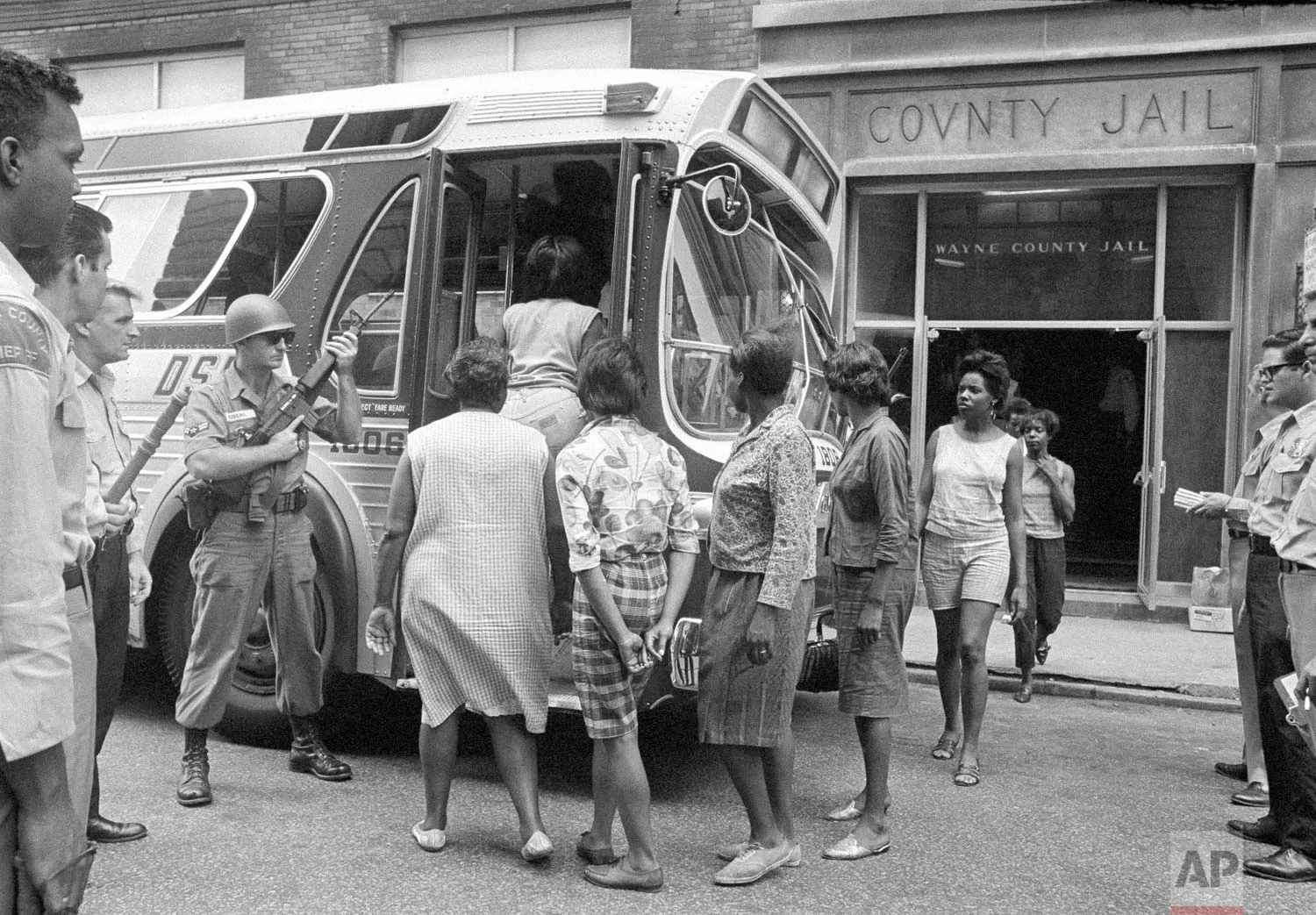 In this July 28, 1967 photo, female prisoners arrested during the rioting in Detroit, board a bus at Wayne County Jail, watched by National Guardsmen for transfer to Eloise, a detention home for women on the edge of the city. Mass arrests of men, women and juveniles had taxed jail facilities in the city. (AP Photo)