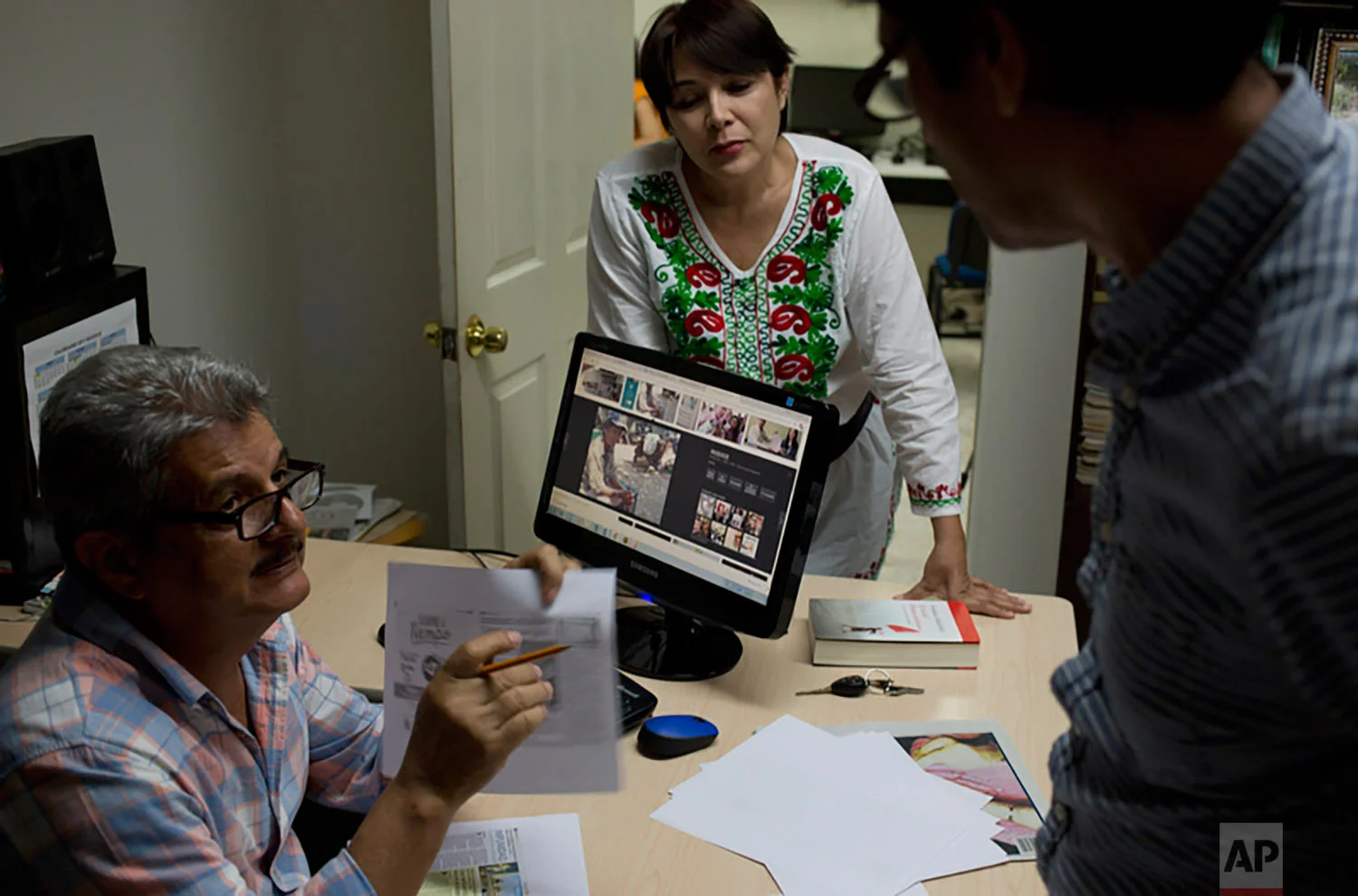 In this June 30, 2017 photo, Ismail Bojorquez, 60, co-founder and director of Riodoce, speaks with editors Andres Villareal and Judith Valenzuela as they prepare the weekly edition at his office in Culiacan, Sinaloa state, Mexico. Bojorquez is wracked with guilt for failing to protect his friend and Riodoce colleague Javier Valdez, who on May 15 was pulled from his vehicle, shot 12 times and left dead on the street. (AP Photo/Enric Marti)