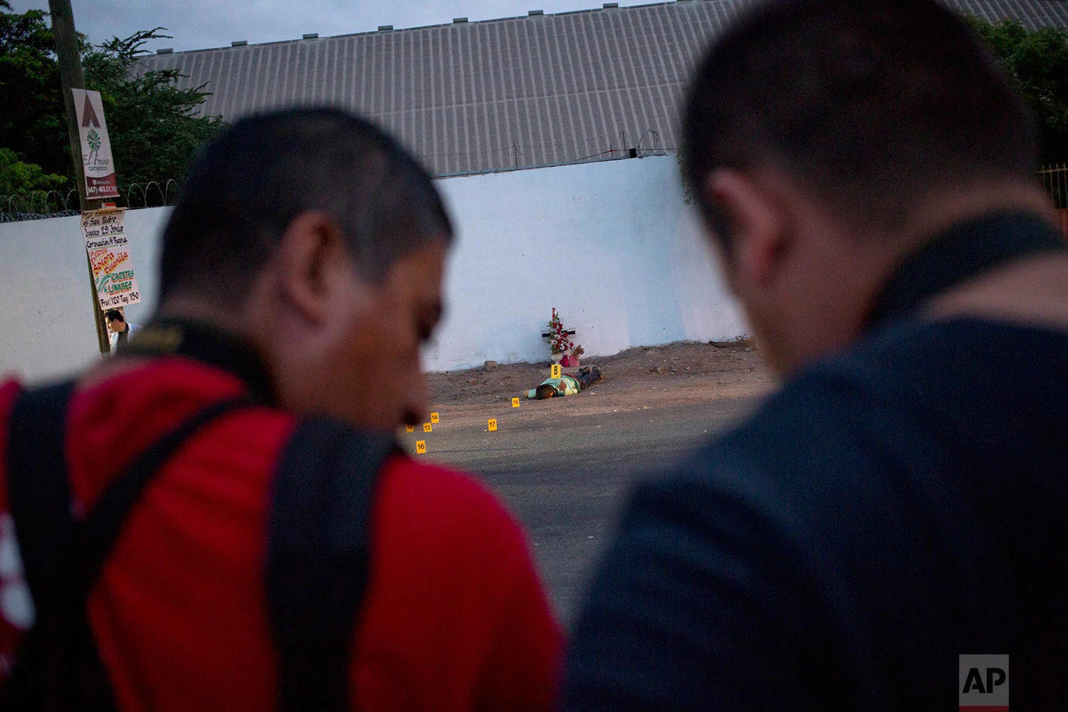 In this June 29, 2017 photo, journalists report from the site where three bullet ridden bodies were found in Navolato, on the outskirts of Culiacan, Sinaloa state, Mexico. Sinaloa is home to the cartel of the same name that was long run by notorious kingpin Joaquin "El Chapo" Guzman. Since Guzman's arrest last year and extradition to the United States in January, Sinaloa has been one of the country's bloodiest battlegrounds as rival factions fight to fill the vacuum. (AP Photo/Enric Marti)