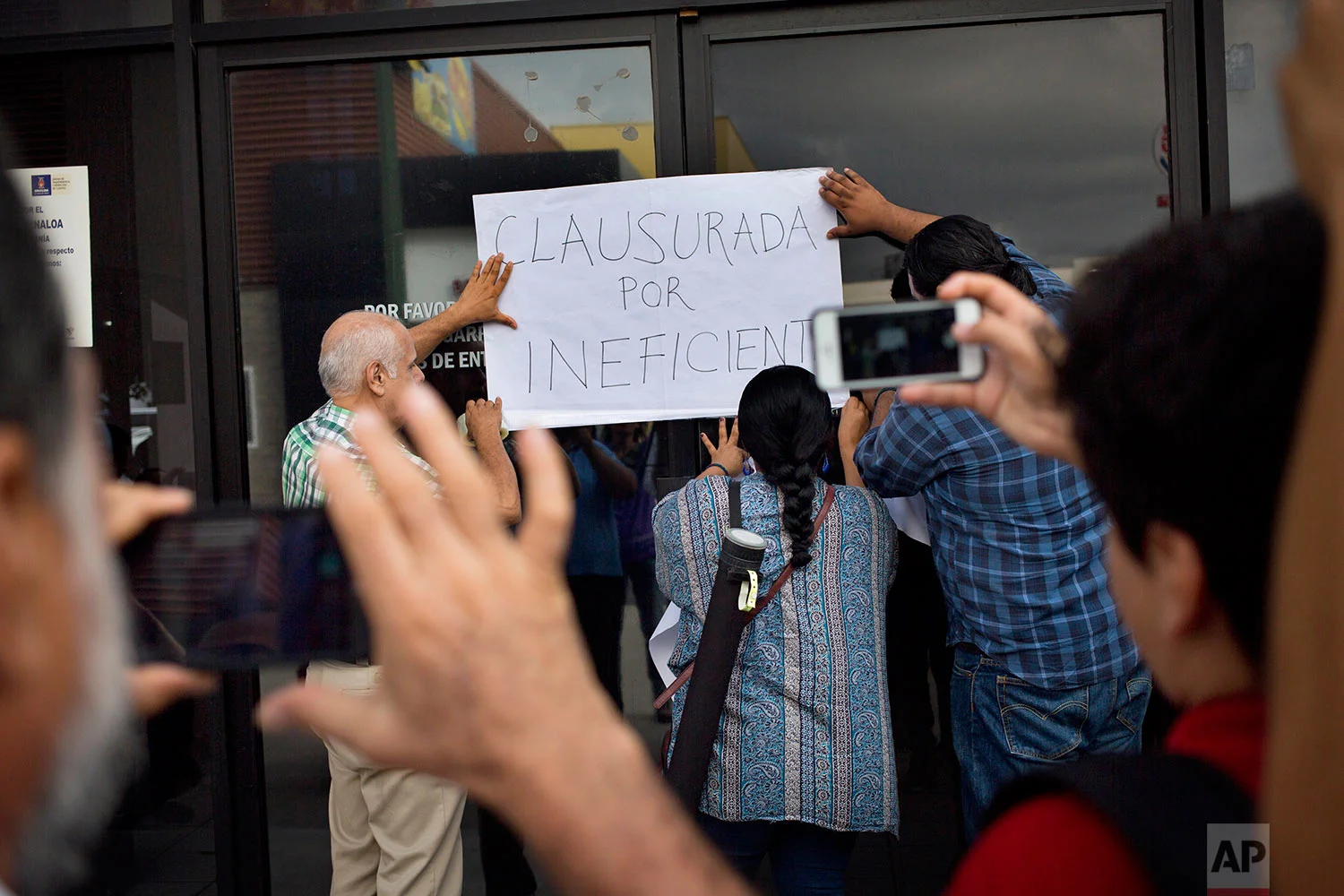 In this June 28, 2017 photo, journalists place a sign that reads in Spanish "closed for being inefficient" during a demonstration at the Sinaloa state attorney's general office, after the killing of yet another journalist, in Culiacan, Sinaloa state, Mexico. The murders of journalists have had a chilling effect. Some outlets have opted to close, such as the newspaper El Norte, in the northern border state of Chihuahua, after the killing of correspondent Miroslava Breach in March. Others keep going, as El Manana of Nuevo Laredo did following the killing of its director in 2004. (AP Photo/Enric Marti)