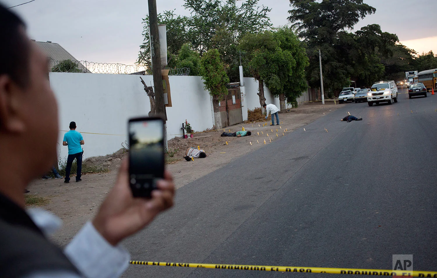 In this June 29, 2017 photo, multimedia journalist Ernesto Martinez, known as "El Pepis," from the local online news website "Linea Directa," reports with his cellphone at the site where three bodies were found in Navolato, on the outskirts of Culiacan, Sinaloa state, Mexico. There are drug-traffickers, politicians, businesspeople, journalists suspected of being on the payroll of the government or the cartels, a catalog of villains who make the job of covering Mexico’s chaos a daily dance of high-risk decisions. (AP Photo/Enric Marti)