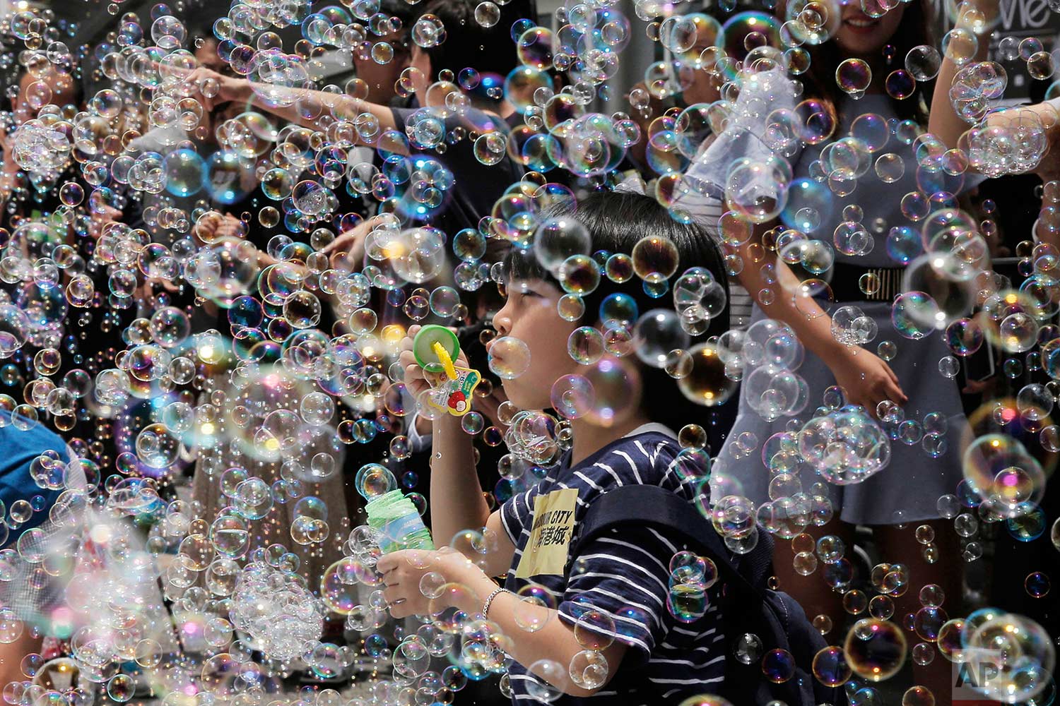 A boy plays with bubbles during an art display titled "Bubble Up" created by Japanese artist Shinji Ohmaki in Hong Kong, Wednesday, Aug. 2, 2017. (AP Photo/Kin Cheung)