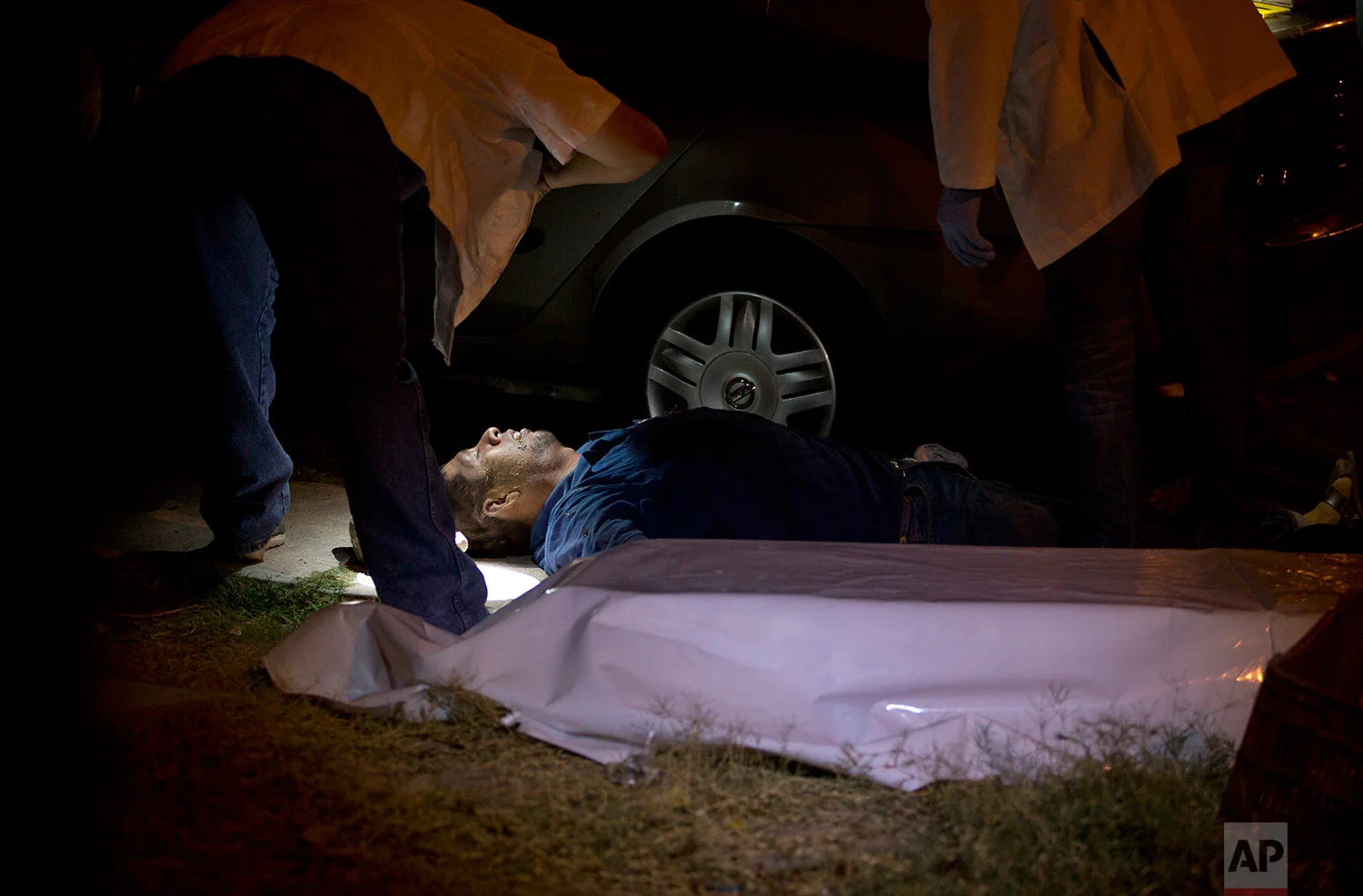 In this early June 29, 2017 photo, forensics inspect the body of a man who was shot in Culiacan, Sinaloa state, Mexico. Sinaloa is home to the cartel of the same name that was long run by notorious kingpin Joaquin "El Chapo" Guzman. Since Guzman's arrest last year and extradition to the United States in January, Sinaloa has been one of the country's bloodiest battlegrounds as rival factions fight to fill the vacuum. (AP Photo/Enric Marti)