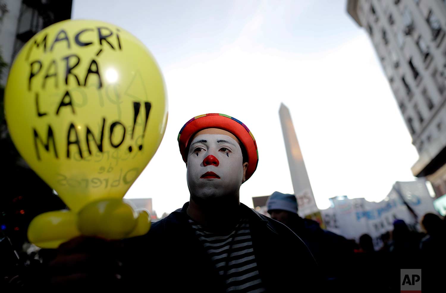 A clown marches with a balloon with text written in Spanish that reads "Macri, take it easy," in Buenos Aires, Argentina, Tuesday, July 18, 2017. (AP Photo/Natacha Pisarenko)