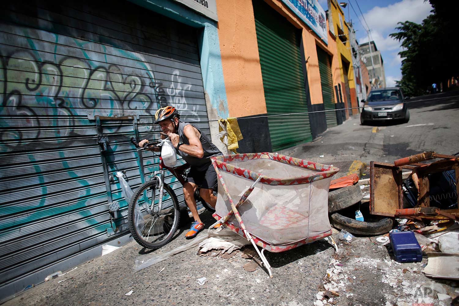 A man who is a resident of Petare neighborhood crosses through a barricade set up by demonstrators to protest against President Nicolas Maduro's plan to rewrite the constitution in Caracas, Venezuela, Saturday, July 29, 2017. (AP Photo/Ariana Cubillos)
