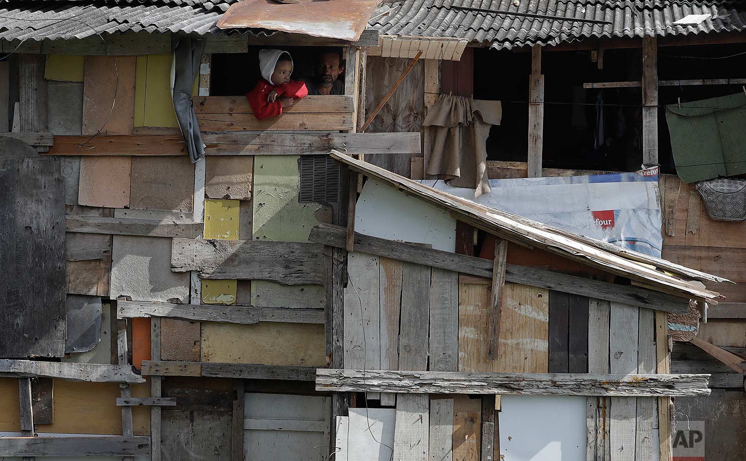 A boy peers from his home's window as firefighters put out the last flames of a nearby fire in Osasco in the greater Sao Paulo area of Brazil, Monday, July 3, 2017. (AP Photo/Andre Penner)