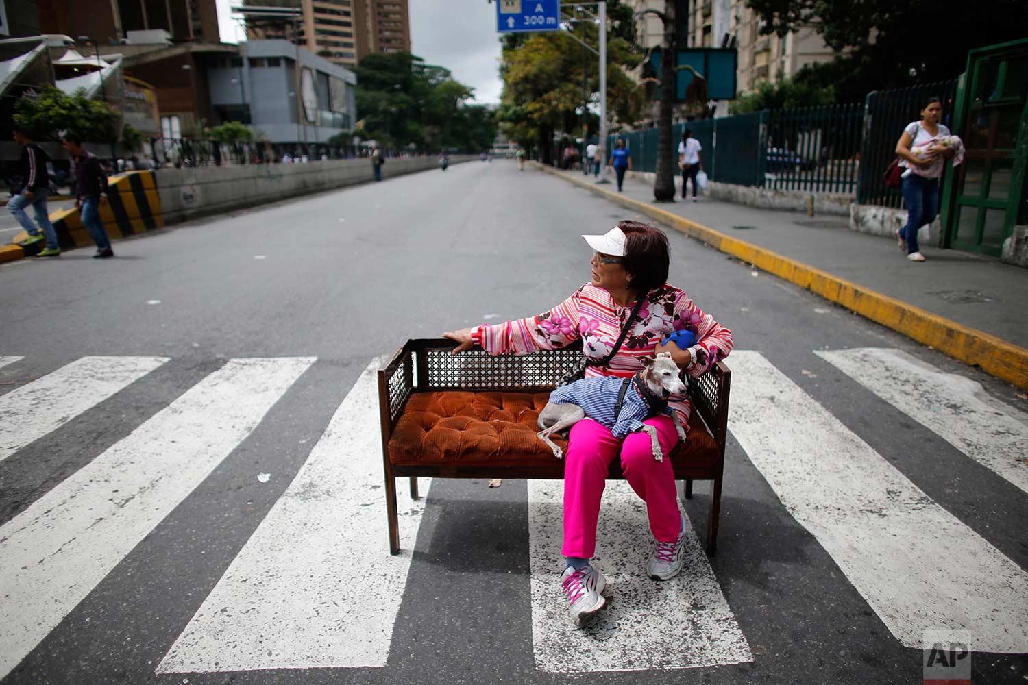 An woman sits with her dog on a couch placed in the middle of the street during a call by the opposition to block roads for 10 hours in Caracas, Venezuela, Monday, July 10, 2017. (AP Photo/Ariana Cubillos)