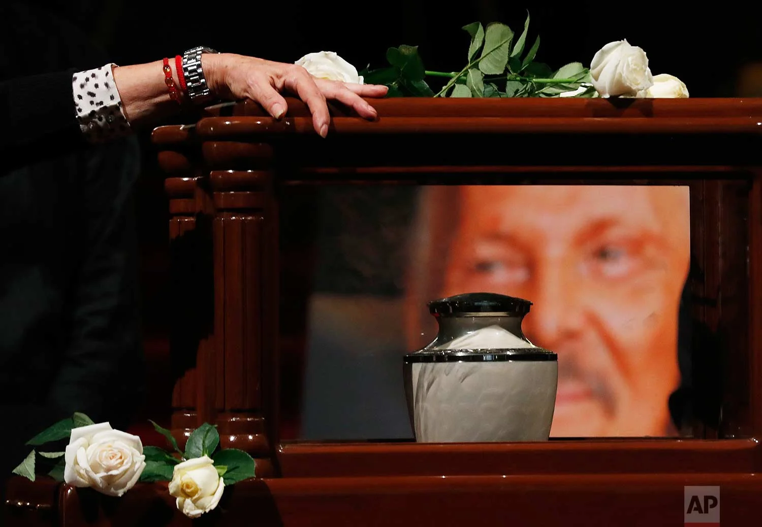 A woman touches the box containing the ashes of of Mexican painter Jose Luis Cuevas, in the Palace of Fine Arts in Mexico City, Tuesday, July 4, 2017. (AP Photo/Eduardo Verdugo)