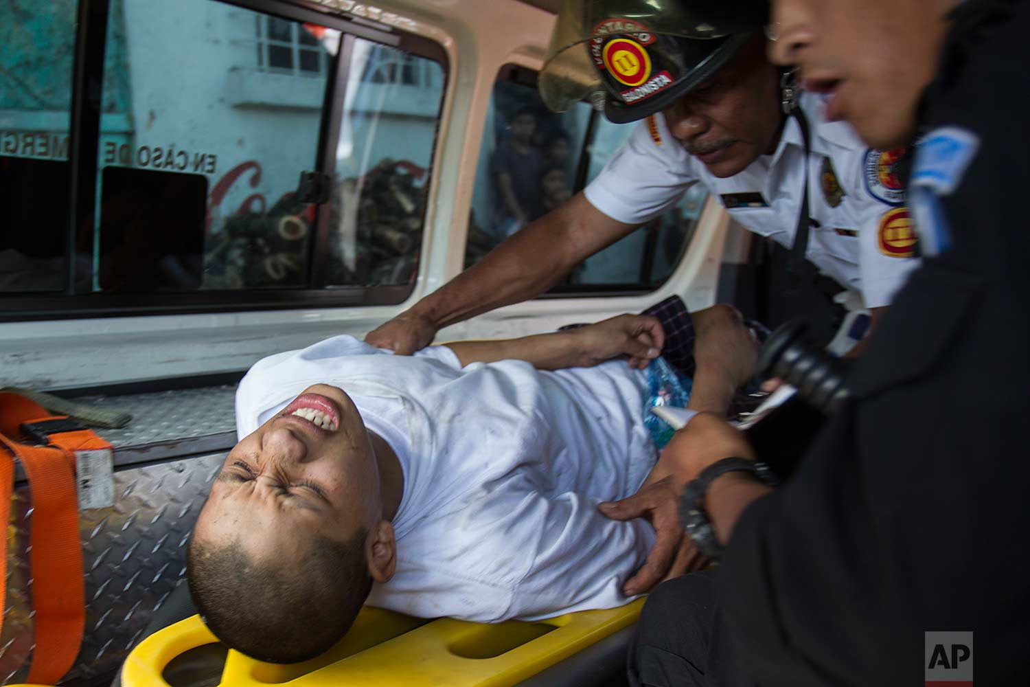 A juvenile inmate is attended by a medic and interrogated by a police officer, after he was injured during the recapture of the Juvenile Correctional Center Gaviotas by police, in Guatemala City, Monday, July 3, 2017. (AP Photo/Moises Castillo)