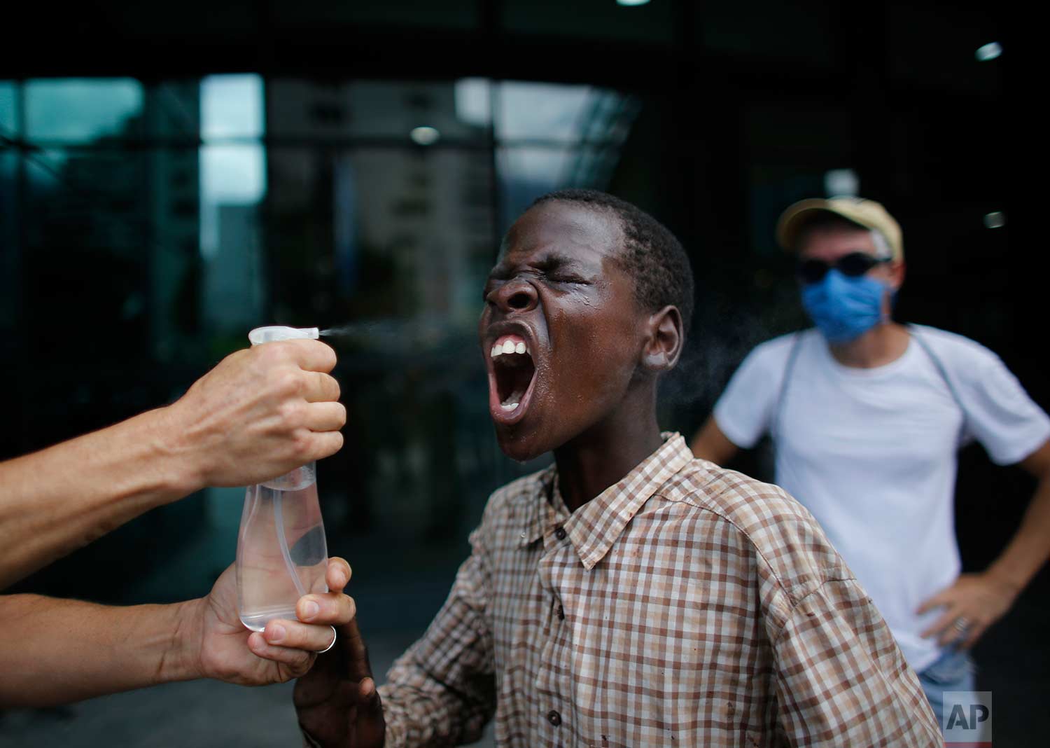 A youth has his face rinsed from the effects of tear gas after security forces lobbed tear gas at demonstrators sheltering inside a shopping mall during a protest march in Caracas, Venezuela, Thursday, July 6, 2017. (AP Photo/Ariana Cubillos)