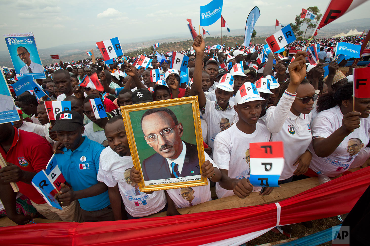 Supporters of Rwanda's President Paul Kagame, portrait center, attend an election campaign rally on the hills overlooking Kigali, Rwanda, Wednesday Aug. 2, 2017. Kagame has been in power since the end of the country's genocide in 1994 and is widely expected to win another term in the Aug. 4 elections after the government earlier this month disqualified all but three candidates. (AP Photo/Jerome Delay)