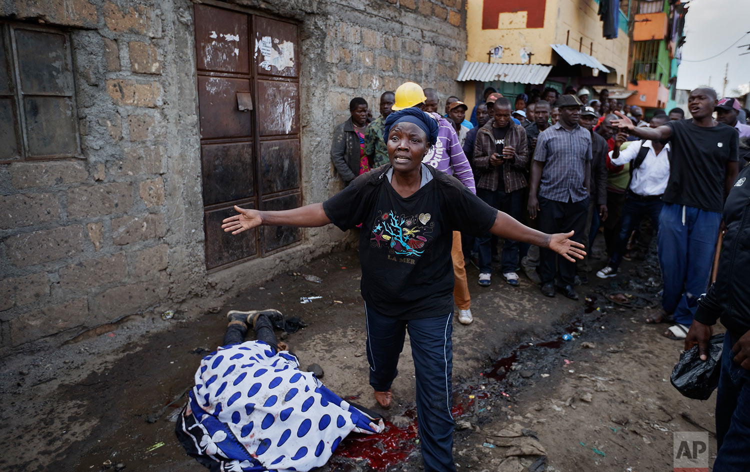 A woman wails in front of the covered body of a man who had been shot in the head and who the crowd claimed had been shot by police, as the angry crowd shouts towards the police, in the Mathare slum of Nairobi, Kenya, Wednesday, Aug. 9, 2017. Kenya's election took an ominous turn on Wednesday as violent protests erupted in the capital. (AP Photo/Ben Curtis)