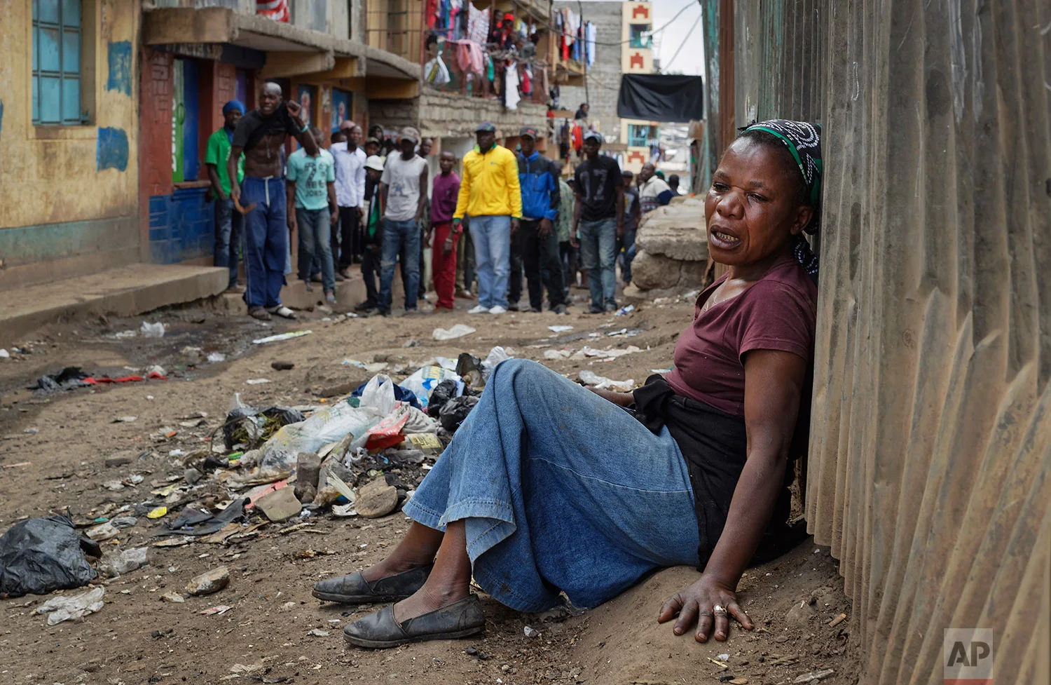 A relative wails on the floor of an alleyway near the body of a man who had been shot in the head and who the crowd claimed had been shot by police, as the angry crowd shouts towards the police, in the Mathare slum of Nairobi, Kenya, Wednesday, Aug. 9, 2017. Kenya's election took an ominous turn on Wednesday as violent protests erupted in the capital. (AP Photo/Ben Curtis)