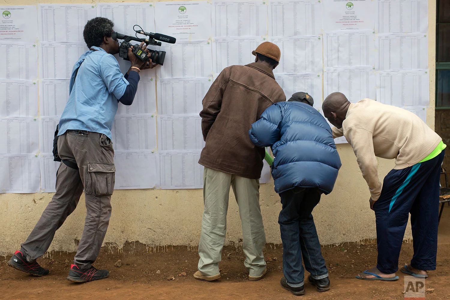 A television cameraman films Kenyans checking if their names are on the electoral lists at a polling station in the Kibera slum in Nairobi, Kenya, Monday, Aug. 7, 2017. Kenyans are due to go to the polls on Aug. 8, to vote in presidential elections after a tightly-fought race between President Uhuru Kenyatta and main opposition leader Raila Odinga. (AP Photo/Jerome Delay)
