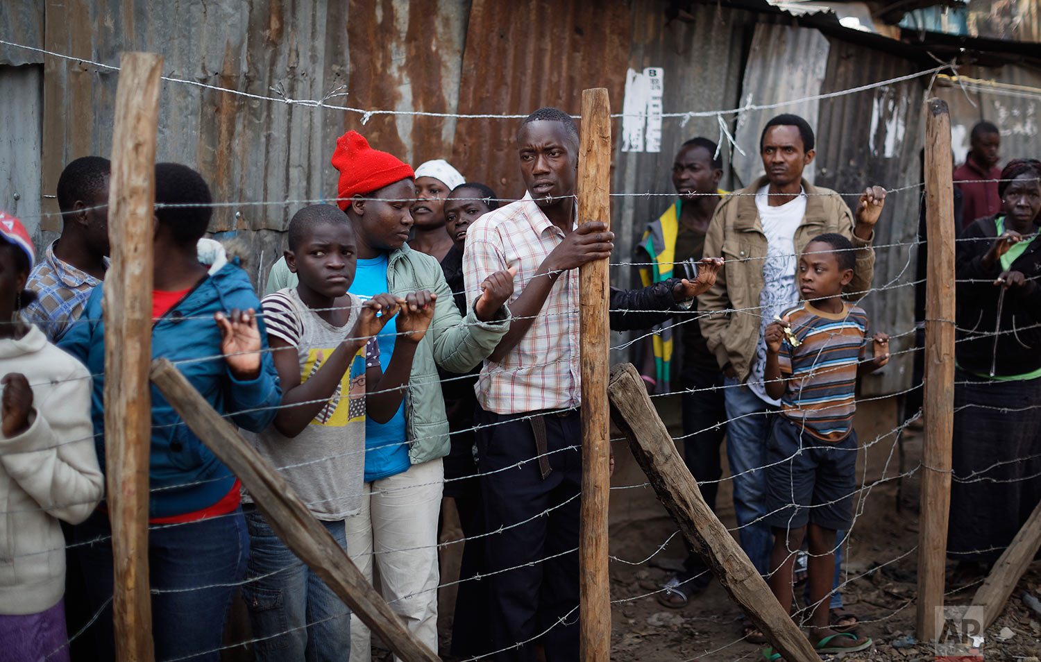  Residents look through a fence at the scene near the body of a man who had been shot in the head and who the crowd claimed had been shot by police, in the Mathare area of Nairobi, Kenya, Wednesday, Aug. 9, 2017. Kenya's election took an ominous turn