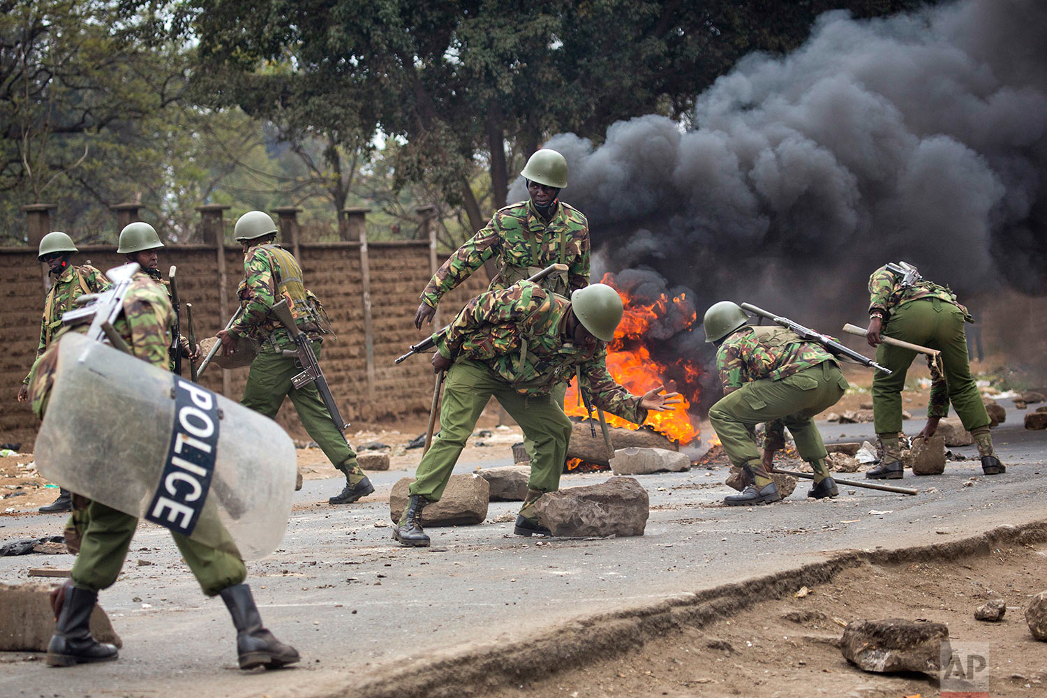  Kenyan security forces remove stones from a street blocked by supporters of Kenyan opposition leader and presidential candidate Raila Odinga who demonstrated in the Mathare area of Nairobi, Wednesday , Aug. 9, 2017. Odinga alleges that hackers manip