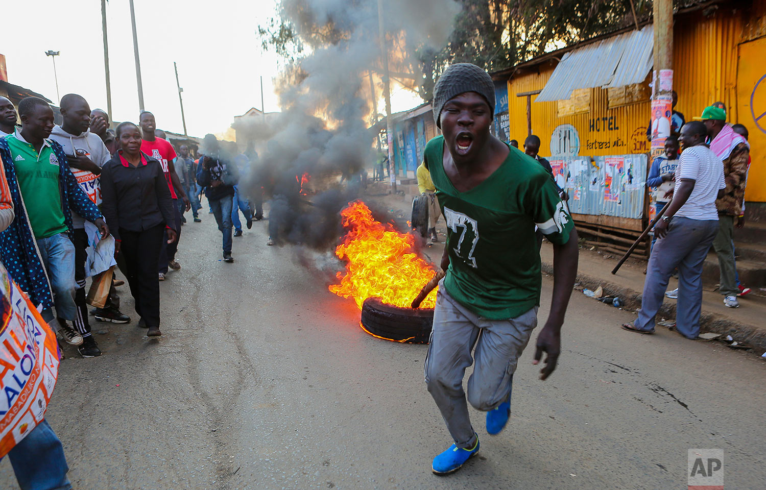  A man pulls a burning tire in Kibera, Nairobi, Kenya, as others block roads with stones to protest in support of Kenyan opposition leader and presidential candidate Raila Odinga, Wednesday, Aug. 9, 2017. Kenya's election took an ominous turn on Wedn