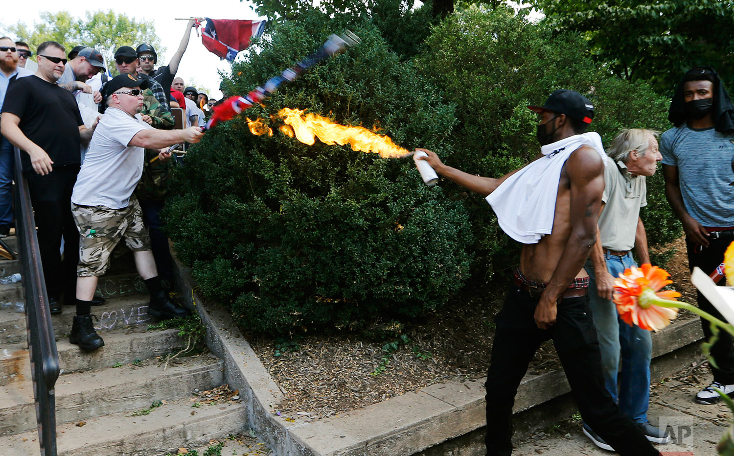  A counter demonstrator uses a lighted spray can against a white nationalist demonstrator at the entrance to Lee Park in Charlottesville, Va., Saturday, Aug. 12, 2017.   Gov. Terry McAuliffe declared a state of emergency and police dressed in riot ge