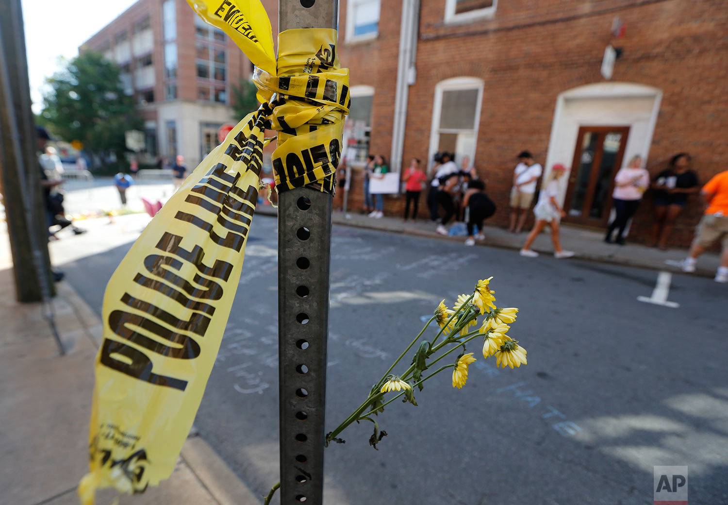  On Sunday, Aug. 13, 2017, police tape and flowers mark the site where a car plowed into a crowd of people protesting a white nationalist rally on Saturday in Charlottesville, Va. (AP Photo/Steve Helber) 