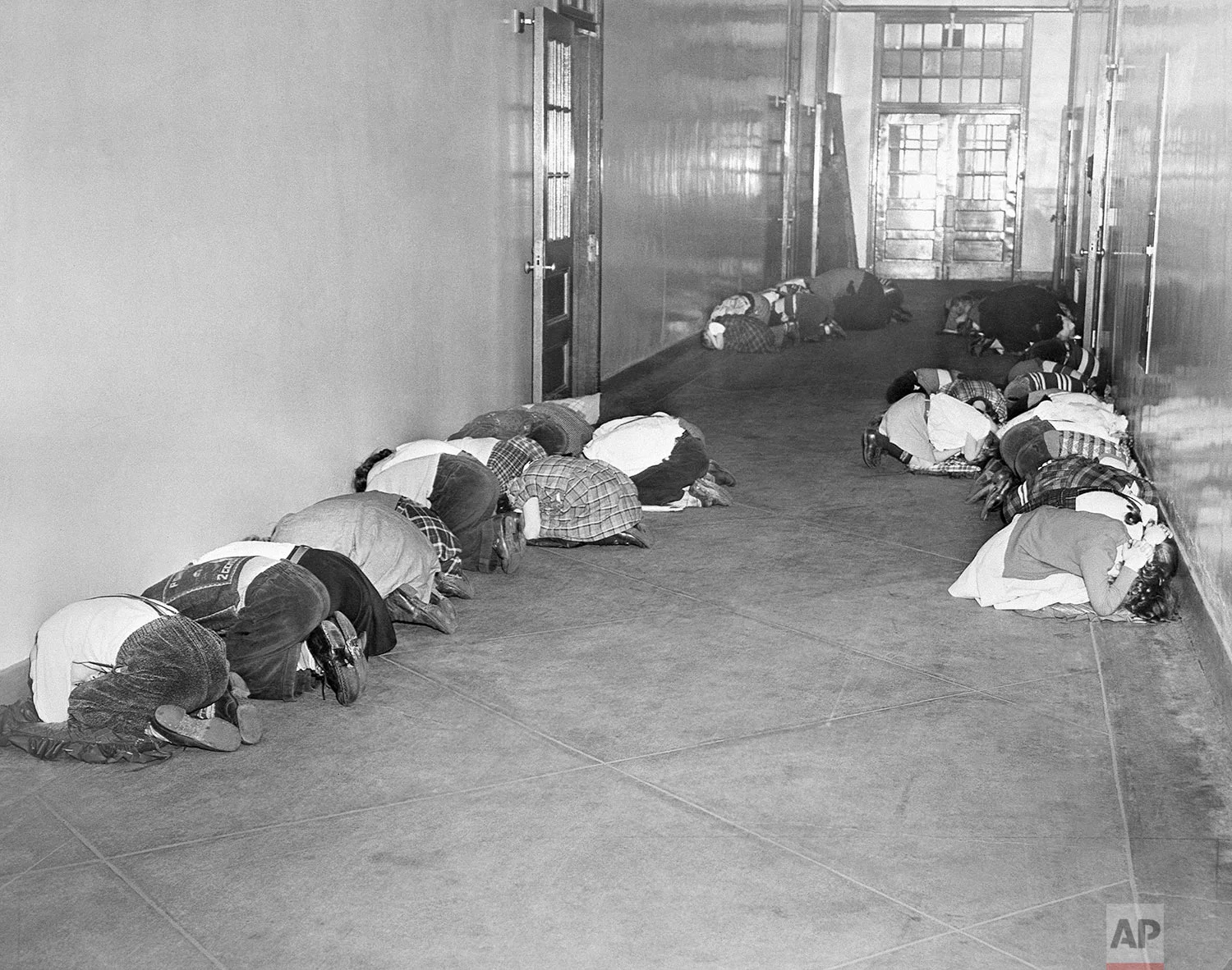 In this Jan. 25, 1951 file photo, students at Thomas Jefferson elementary school kneel in the hallway during an air raid drill being practiced by public schools in Baltimore. (AP Photo)