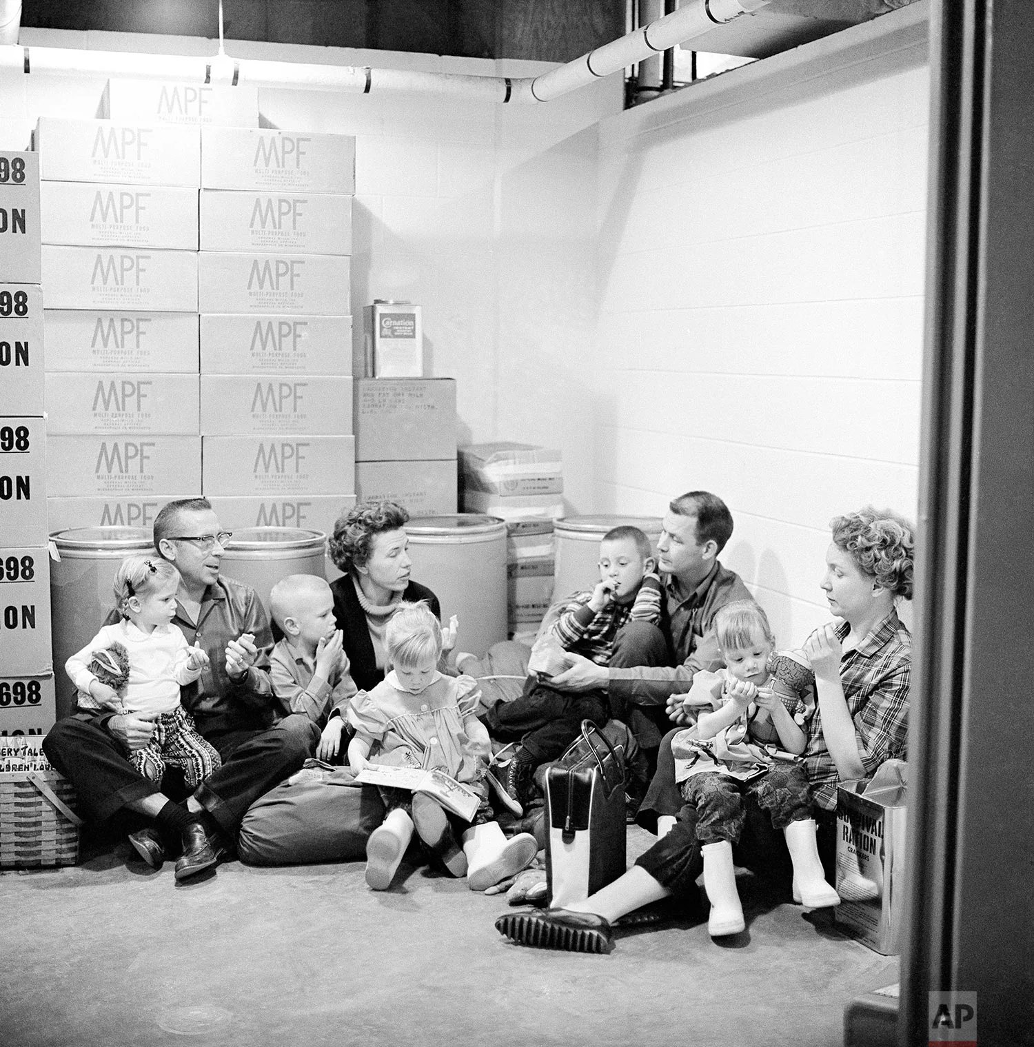 In this Jan. 29, 1962 photo, the Spalding family, left, and the Richmond family demonstrate how people of the town would sit out a nuclear attack and its radioactive aftermath in Los Alamos, N.M., birthplace of the atomic and hydrogen bombs. (AP Photo)
