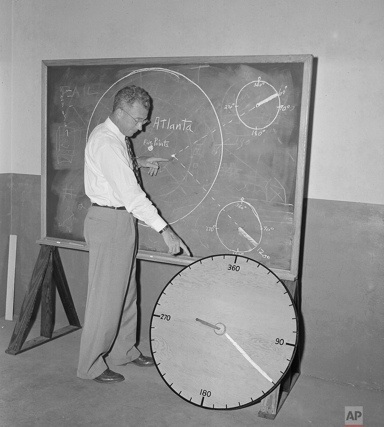 Civil Defense director George M. Phillips of the Atlanta, Ga., area, illustrates he use of a "flash dial", a simple wooden disc, 36 inches in diameter, created to spot the heart of any atomic explosion within a matter of minutes, in Atlanta, June 16, 1951. The disc has a center pole which casts a "shadow" when heat waves from an atomic blast sear the surface of the wood. (AP Photo/Horace Cort)